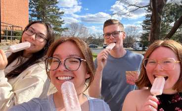 students smiling outside and tasting pink frozen dessert bars