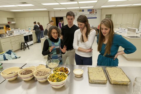 students and instructor looking at various dishes in kitchen lab