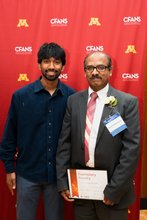 Kumar and his son posing with award and cfans backdrop